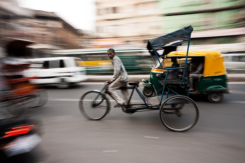 Panning Shot of a cycle rickshaw in downtown traffic Delhi India Daily 