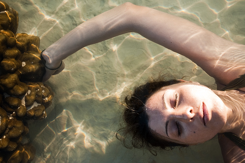 A French woman floats next to a patch of coral in the shallow ocean. -