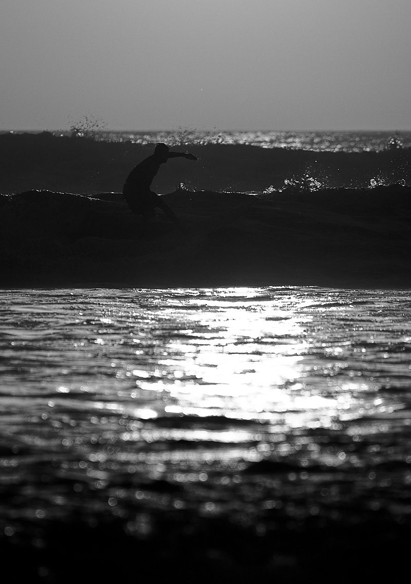 A surfer at sunset rides a wave. - Kuta, Bali, Indonesia  - Daily Travel Photos