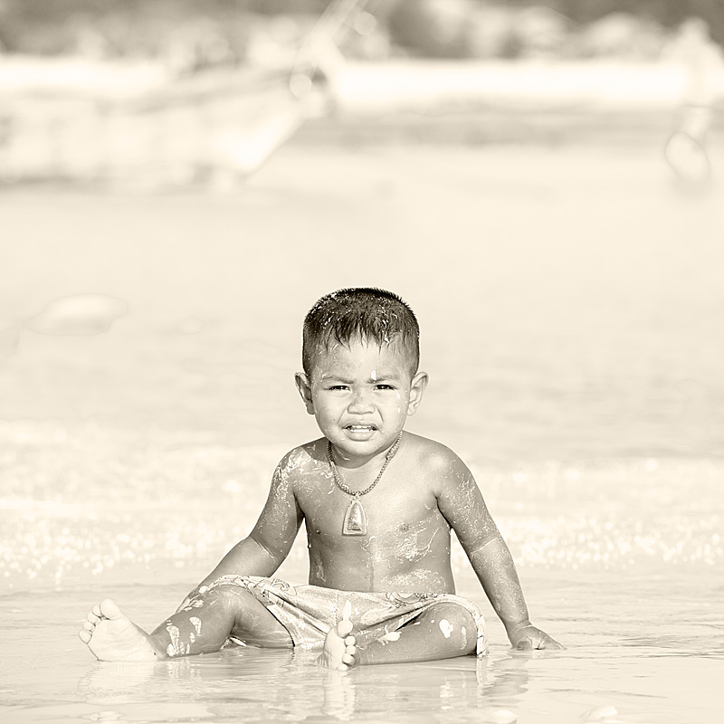 A small Thai boy plays in the muddle sand at low tide. - Ko Lipe, Thailand - Daily Travel Photos