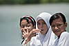 Girls in White (Kinabatangan River Part I) Photo: Three young Malaysian children ride the school-boat on the Kinabatangan River after a long day of classes.