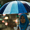 Rainy Day Blues (& Pinks) Photo: A Muslim woman remains dry during a typical Malaysian downpour.