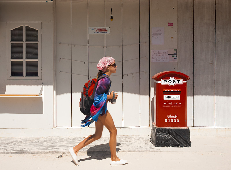 A young Swedish girl takes a morning walk holding a beverage. - Ko Lipe, Thailand - Daily Travel Photos