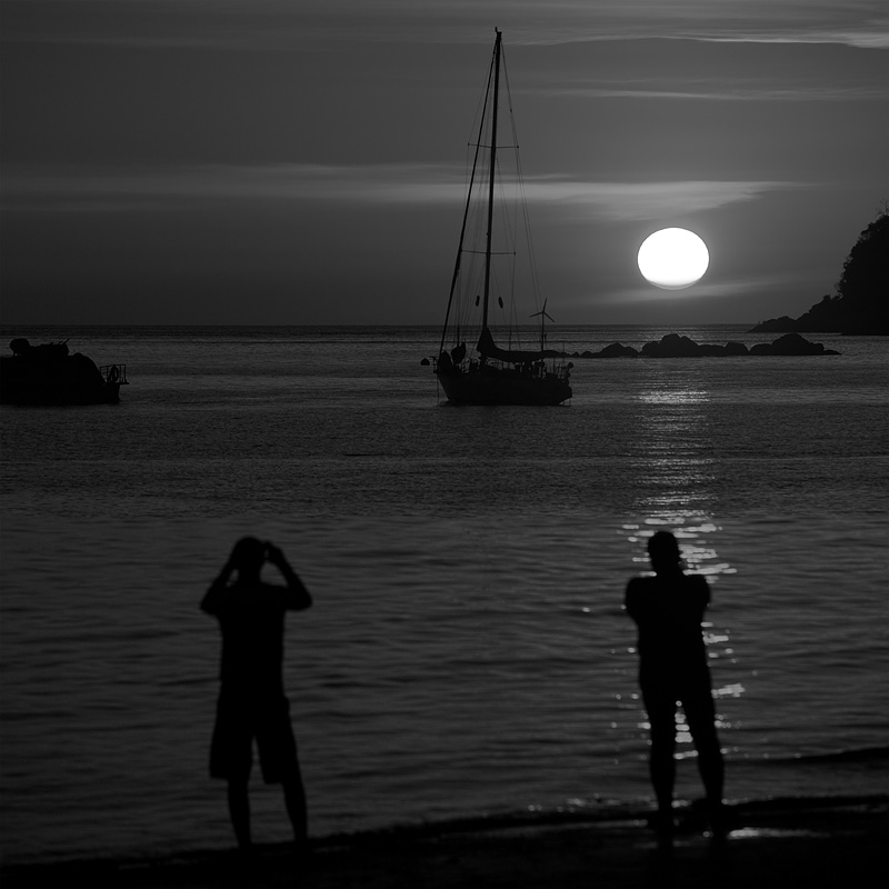 A pair of tourists capture a photo of the setting sun. - Ko Lipe, Thailand - Daily Travel Photos