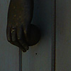 Limp Limb Photo: A metal hand grasping a ball swing on a hinge for a door knocker.